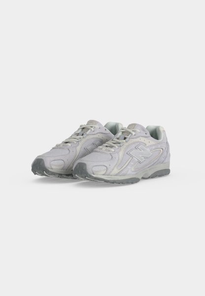 Par de zapatillas deportivas de color gris claro con cordones y suelas texturizadas, colocadas una al lado de la otra sobre un fondo blanco liso.