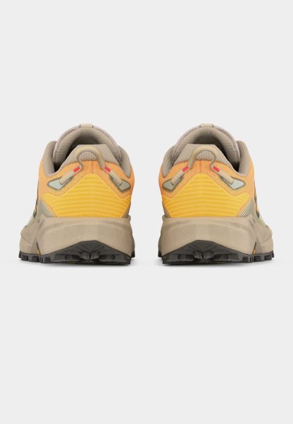 Par de zapatillas para correr por senderos en colores naranja y beige, vistas desde atrás mostrando cuellos acolchados, lengüetas para tirar y suelas negras texturizadas.