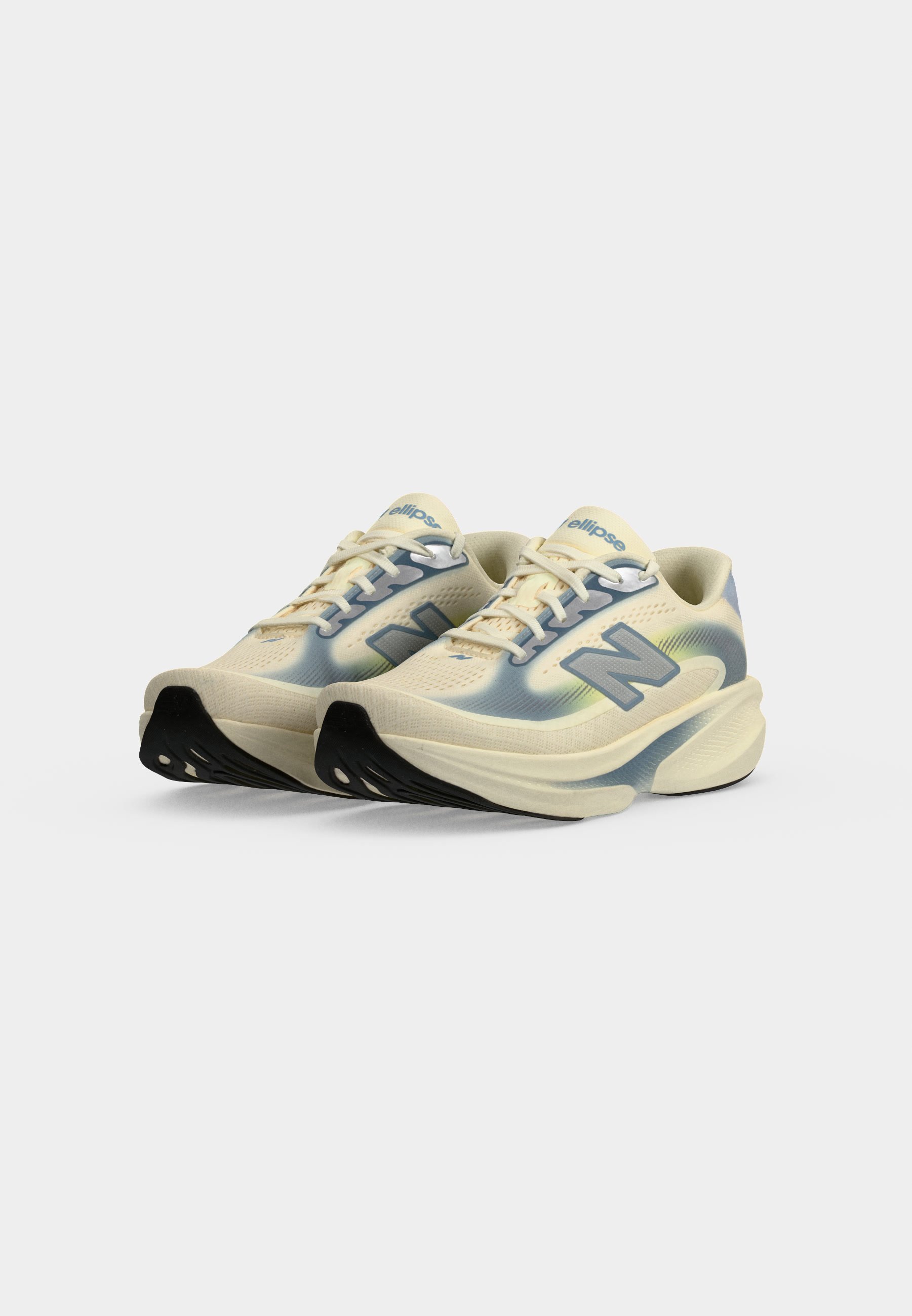 Par de zapatillas de correr crema y azul claro con suelas gruesas y punteras negras, con el logo "N" en los lados.