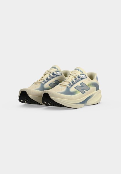 Par de zapatillas de correr crema y azul claro con suelas gruesas y punteras negras, con el logo "N" en los lados.