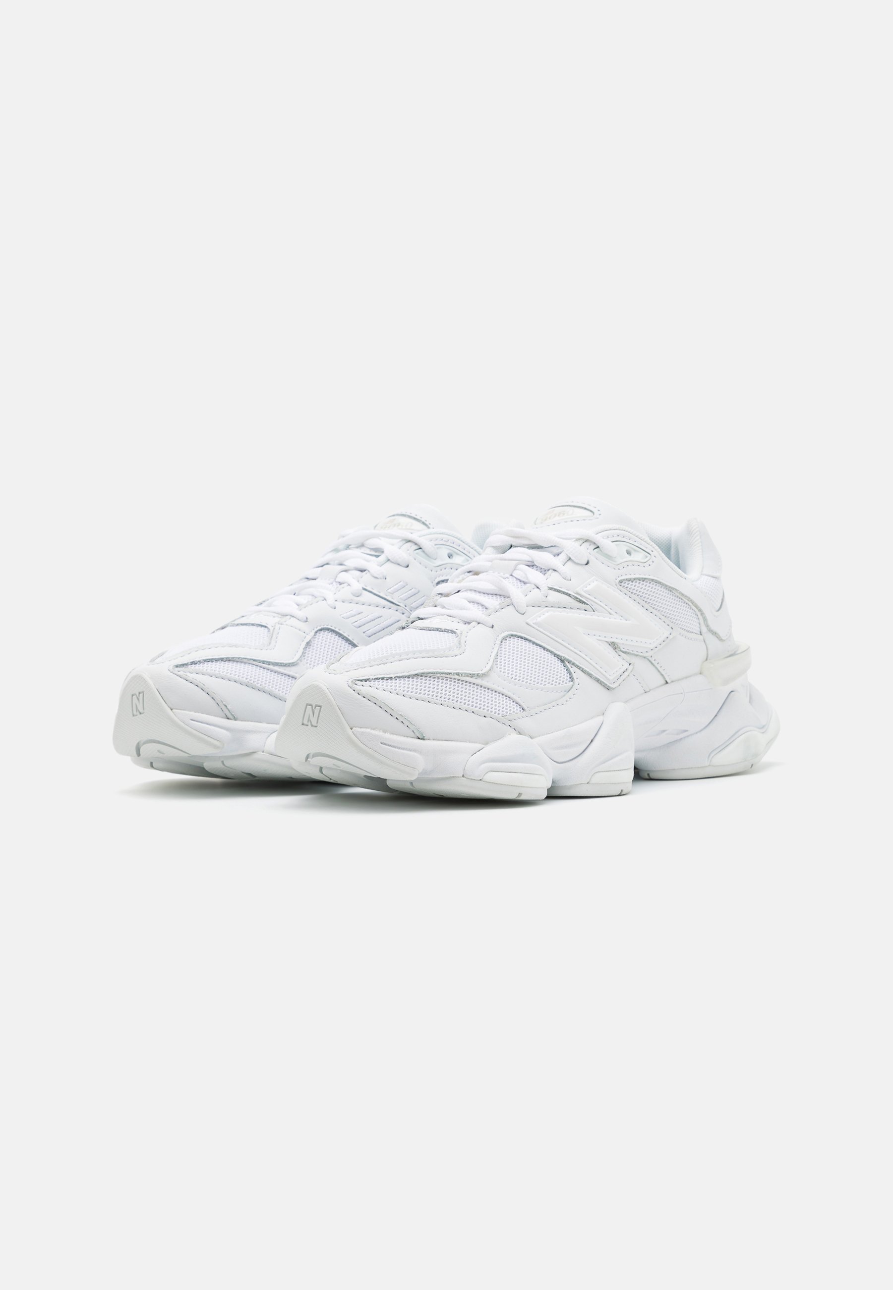 Zapatillas deportivas blancas con parte superior de malla, diseño en capas, suela acolchada y acentos texturizados. Cuentan con cordones y un logo en el costado.