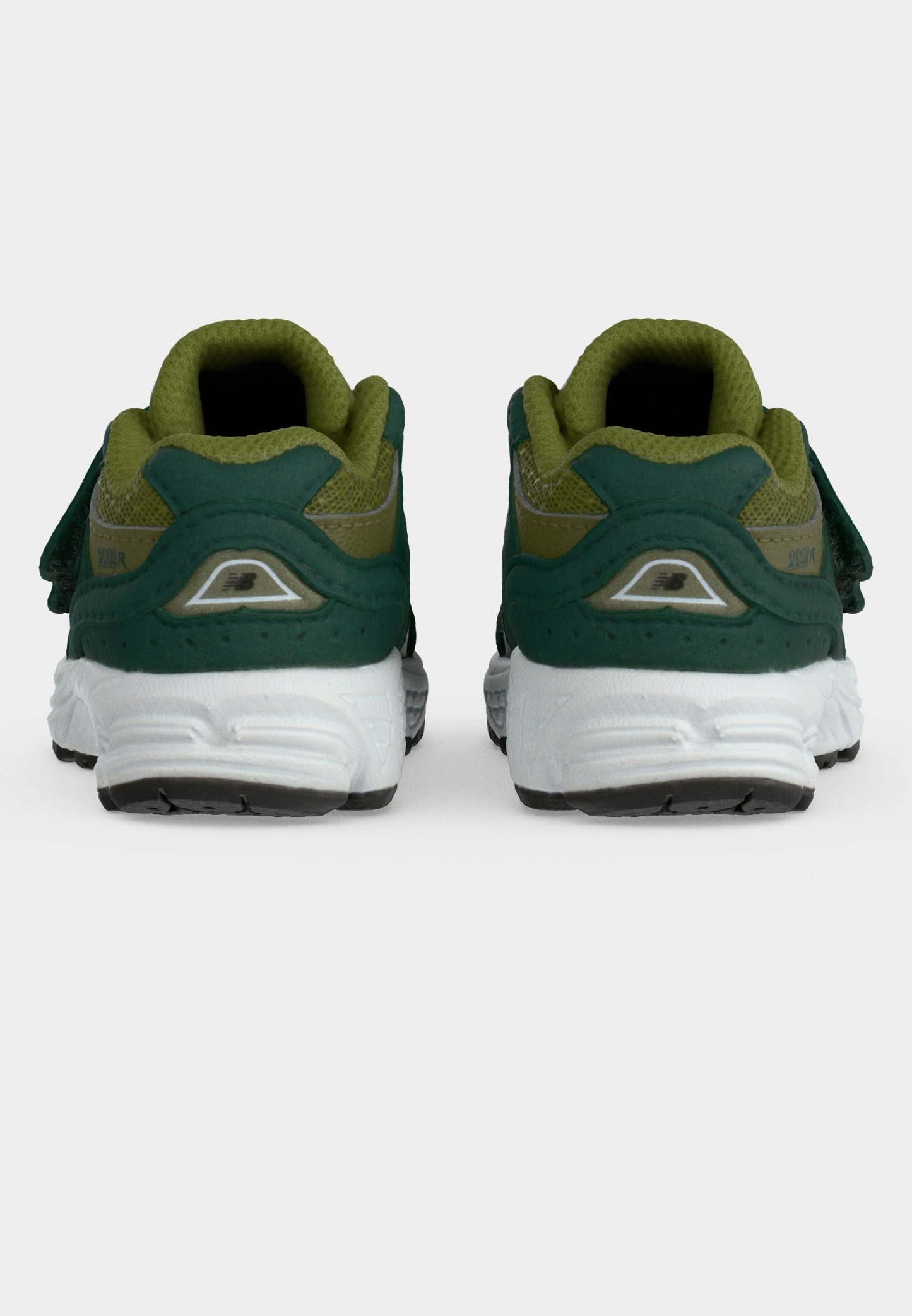 Par de zapatillas deportivas verdes y oliva con suelas blancas vistas desde atrás sobre un fondo claro y liso.
