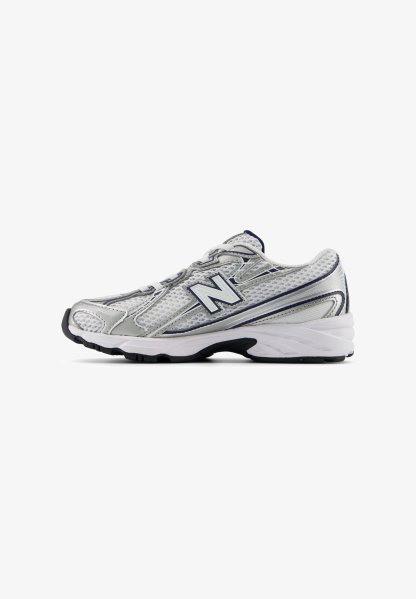 Zapatilla de correr plateada con parte superior de malla, media suela blanca y suela exterior negra. Presenta acentos en azul marino y un prominente logo "N" en el lado.