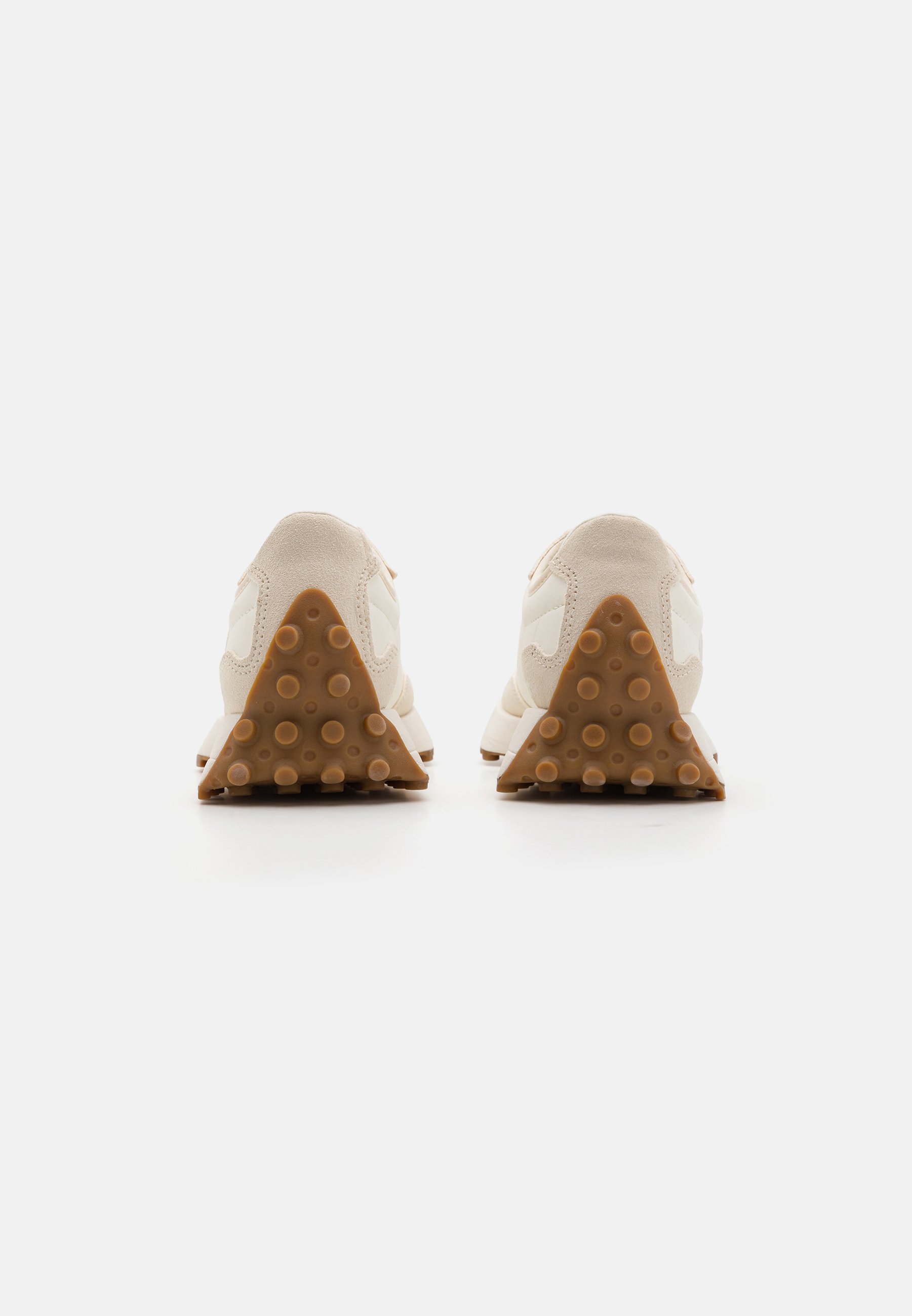 Zapatillas beige con parte superior de ante y acentos en blanco. Cuentan con una suela de goma texturizada en forma triangular y con puntos elevados.