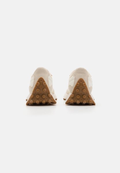 Zapatillas beige con parte superior de ante y acentos en blanco. Cuentan con una suela de goma texturizada en forma triangular y con puntos elevados.