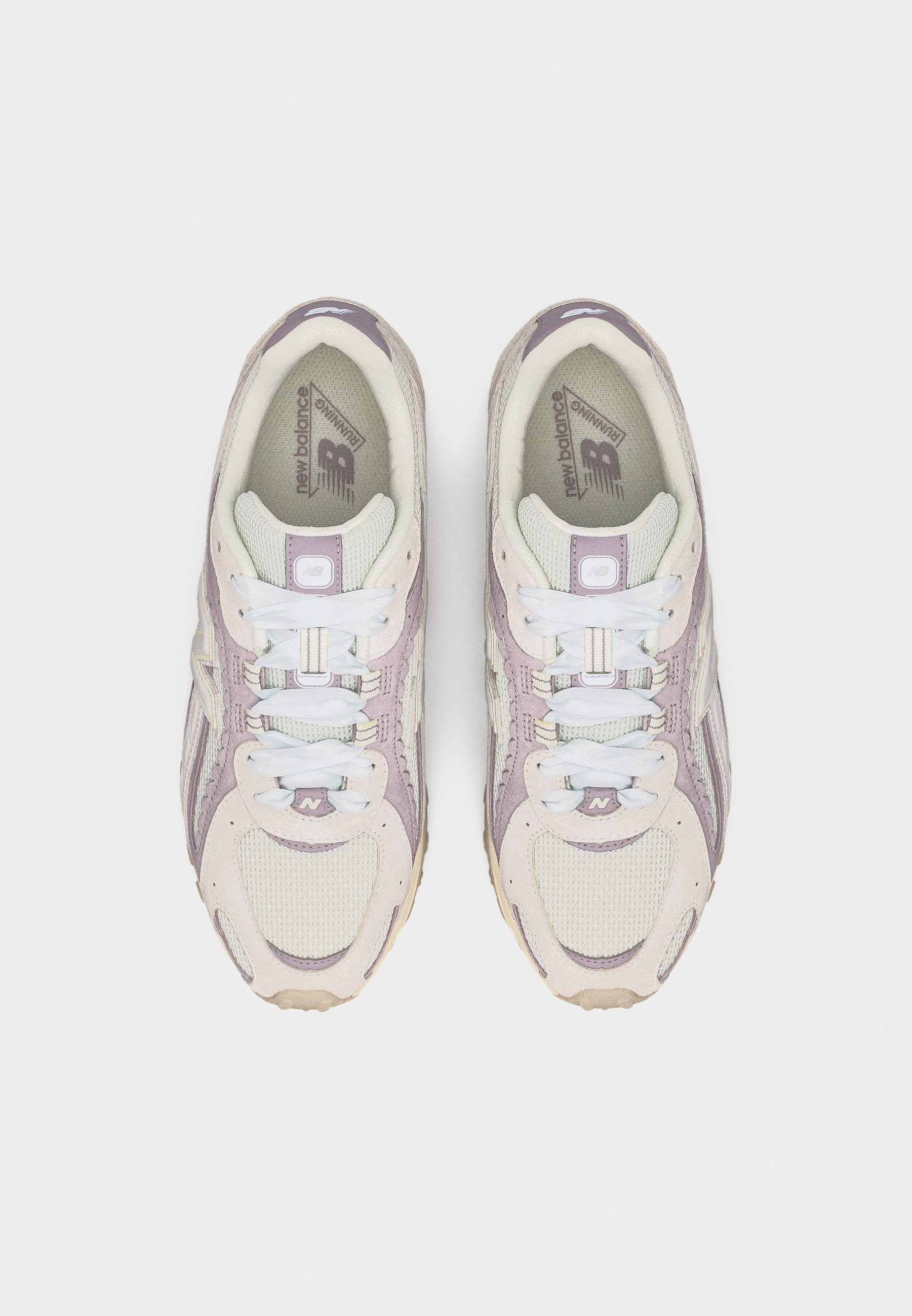Par de zapatillas para correr New Balance en rosa claro y beige con cordones blancos, vista desde arriba sobre un fondo blanco.