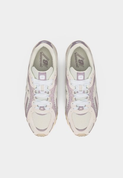 Par de zapatillas para correr New Balance en rosa claro y beige con cordones blancos, vista desde arriba sobre un fondo blanco.