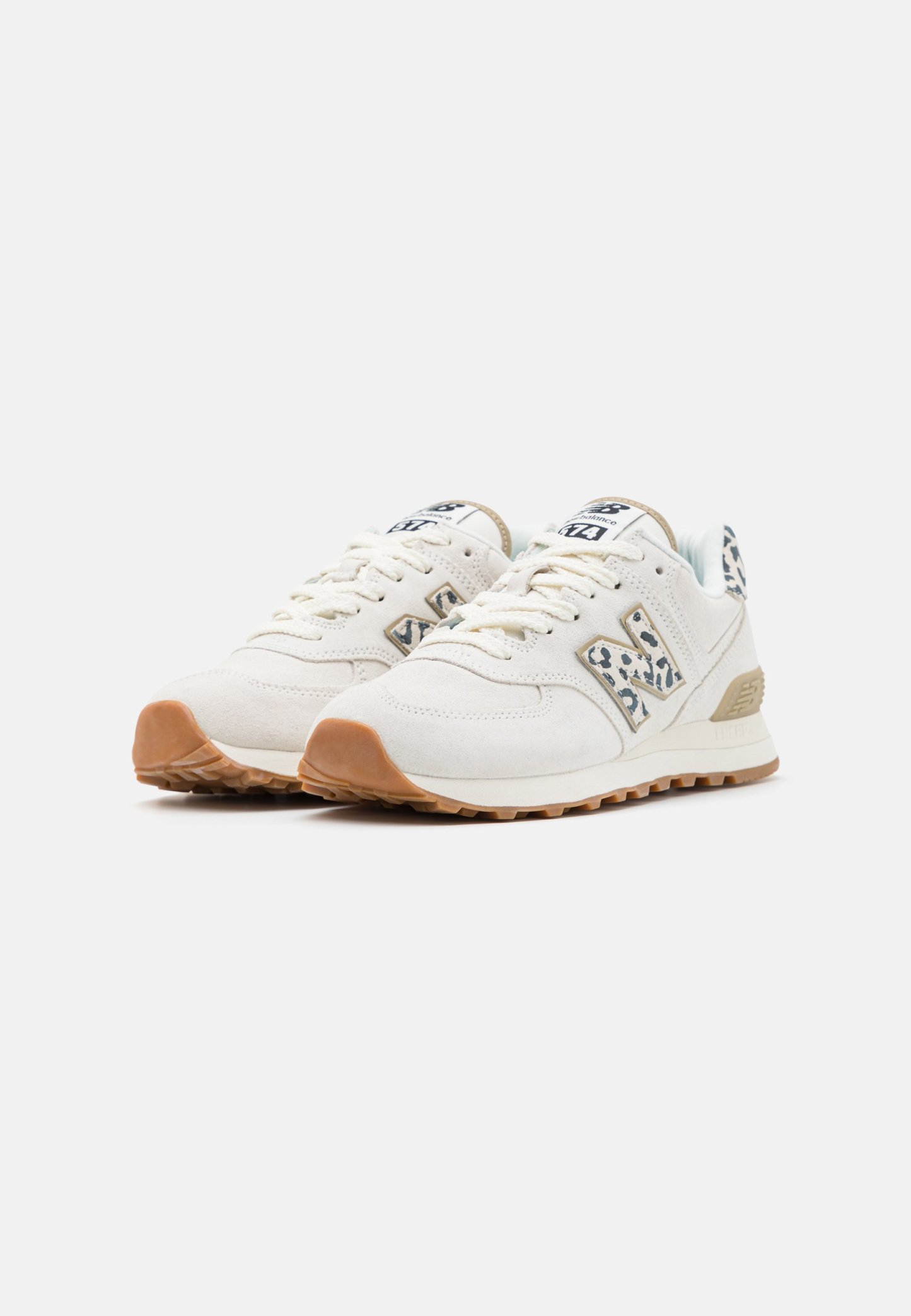 Par de zapatillas de color blanco roto con suelas de goma y detalles con estampado de leopardo en el logo y la lengüeta del talón, colocadas lado a lado sobre un fondo blanco.