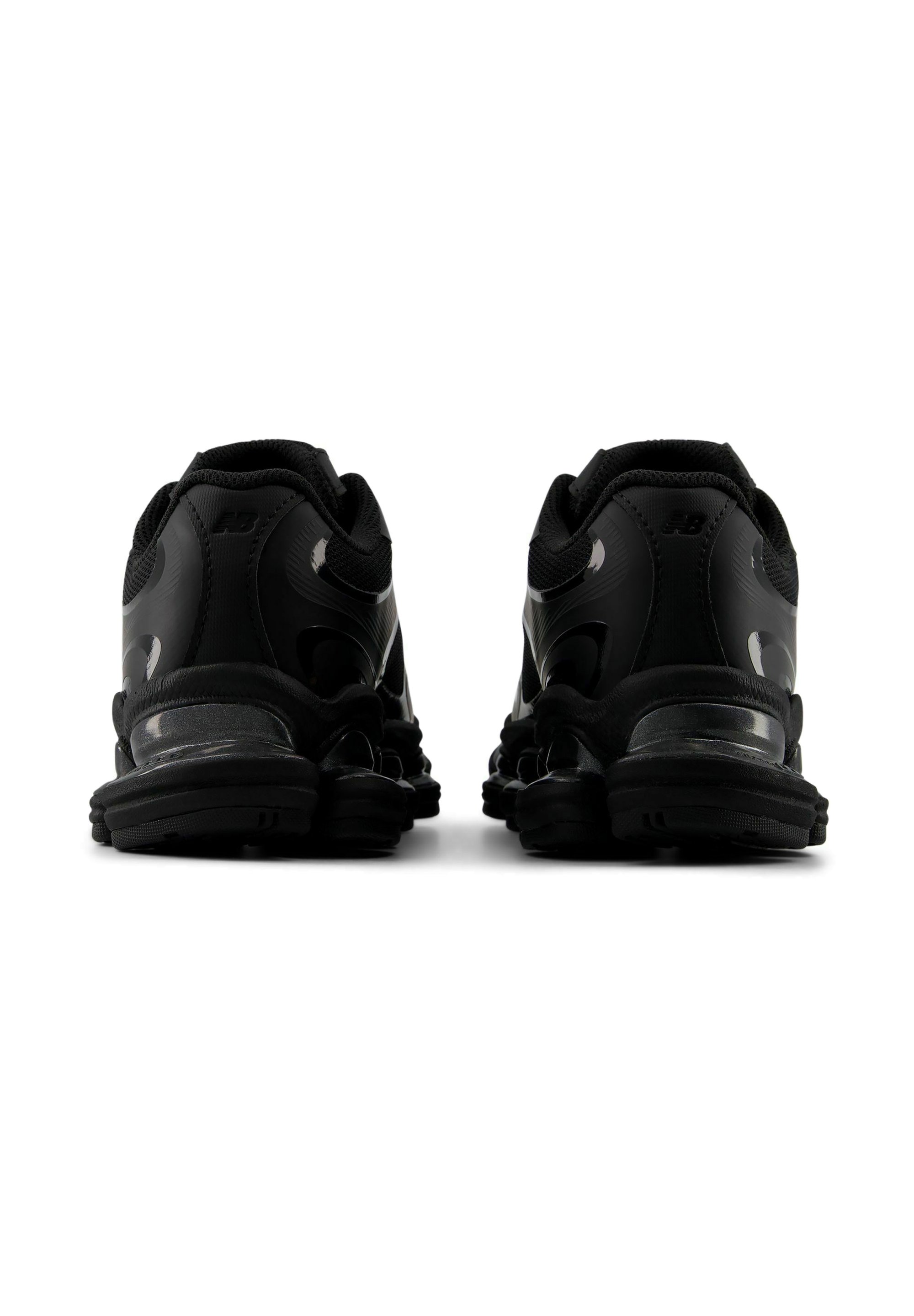 Par de zapatillas deportivas negras vistas desde atrás, mostrando talones acolchados, suelas texturizadas y un diseño bajo.