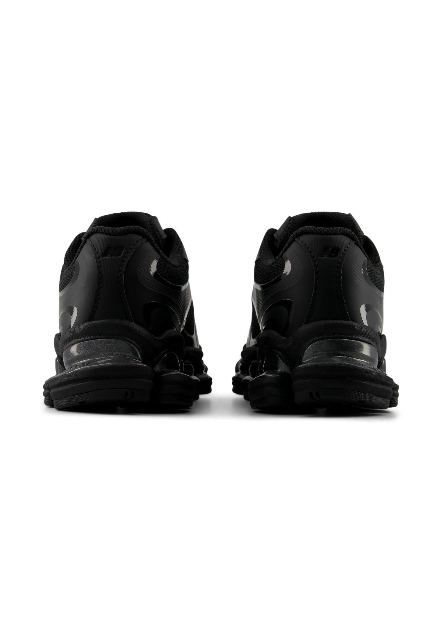 Par de zapatillas deportivas negras vistas desde atrás, mostrando talones acolchados, suelas texturizadas y un diseño bajo.