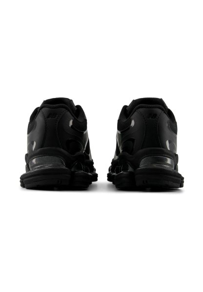 Par de zapatillas deportivas negras vistas desde atrás, mostrando talones acolchados, suelas texturizadas y un diseño bajo.