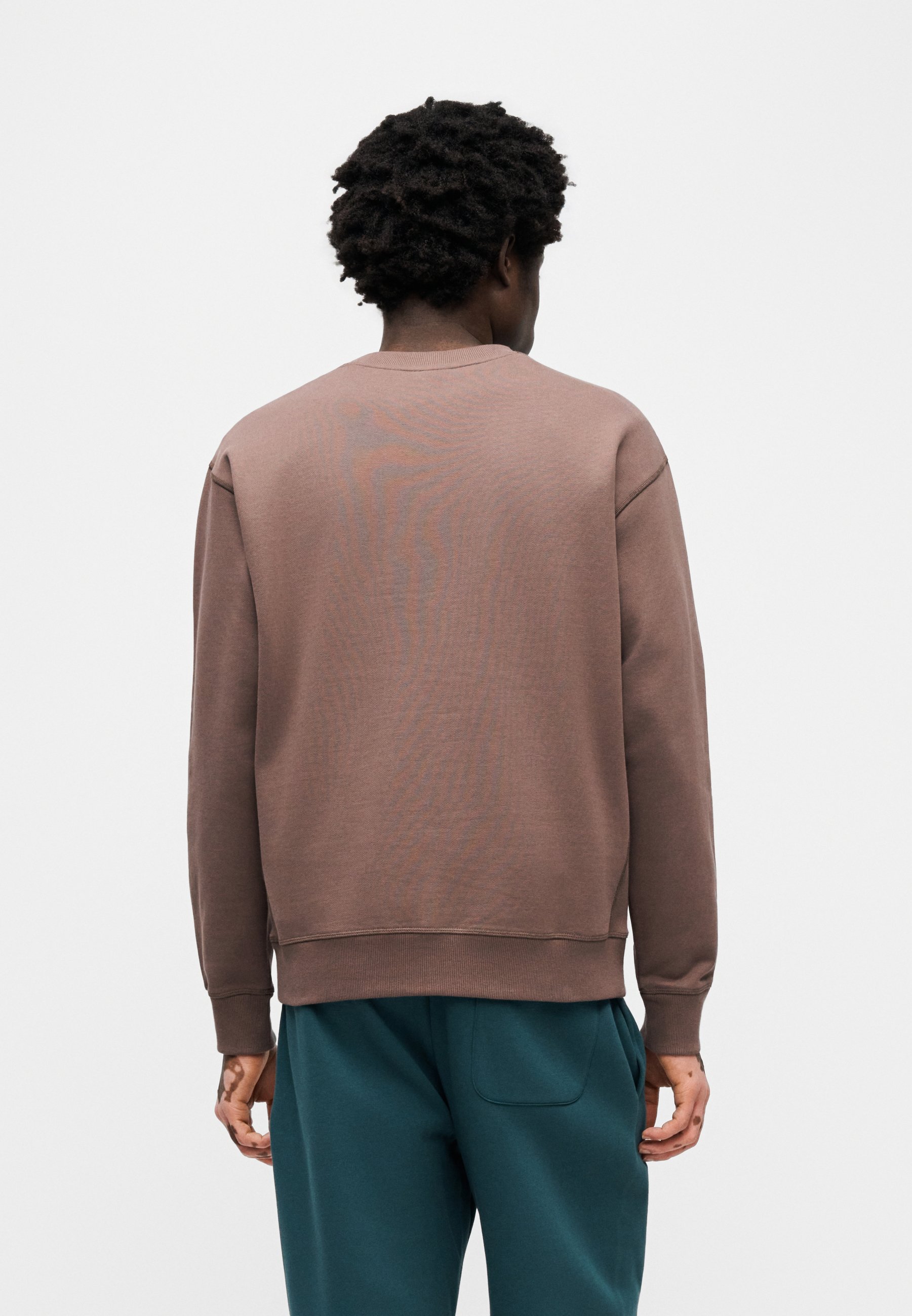 Sudadera marrón con cuello y puños acanalados, de corte holgado y textura suave, combinada con pantalones verde azulado.