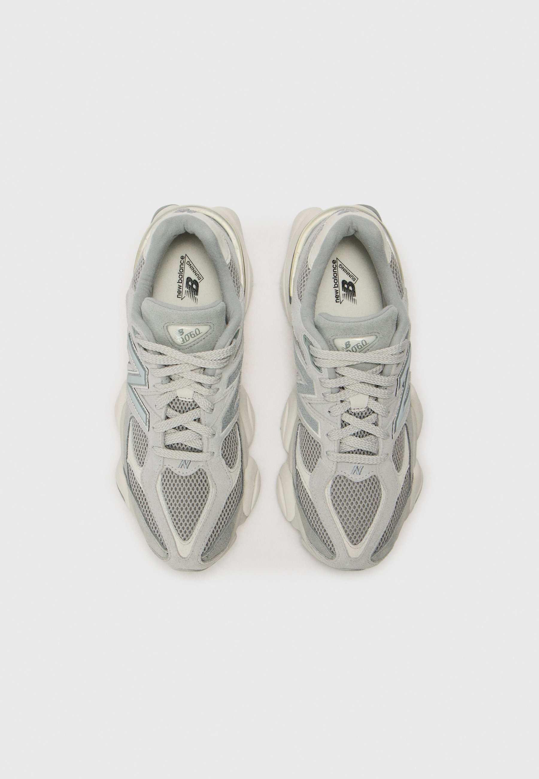 Par de zapatillas de running New Balance 9060 en gris y blanco vistas desde arriba sobre un fondo claro.
