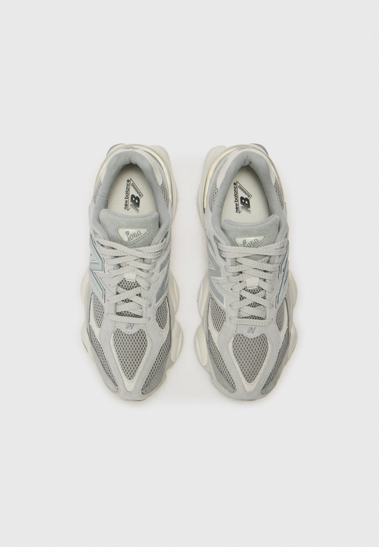 Par de zapatillas de running New Balance 9060 en gris y blanco vistas desde arriba sobre un fondo claro.