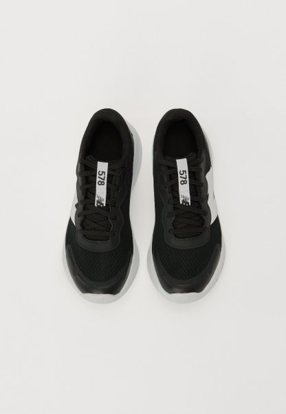 Zapatillas deportivas negras con tejido de malla, cordones negros y acentos blancos. Presenta una suela de goma texturizada y una etiqueta prominente que dice "578".