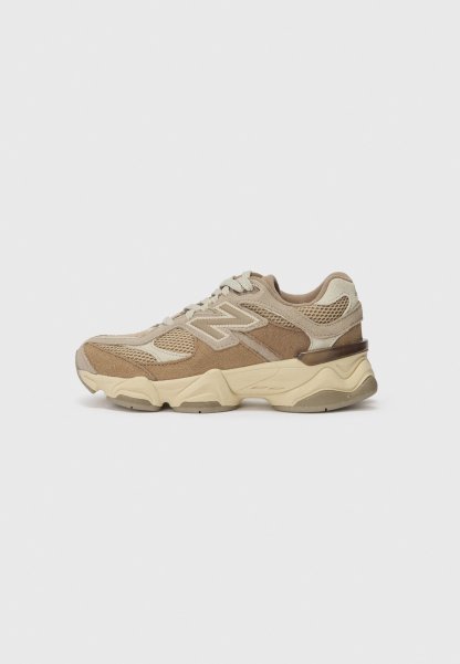 Zapatilla deportiva en beige y marrón, con materiales de malla y ante, acentos texturizados, puntera redondeada y suela de goma gruesa.