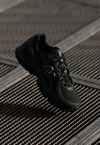 Zapatilla deportiva negra con un upper sintético texturizado, diseño de cordones y acentos plateados, que cuenta con una suela acolchada y una silueta moderna.