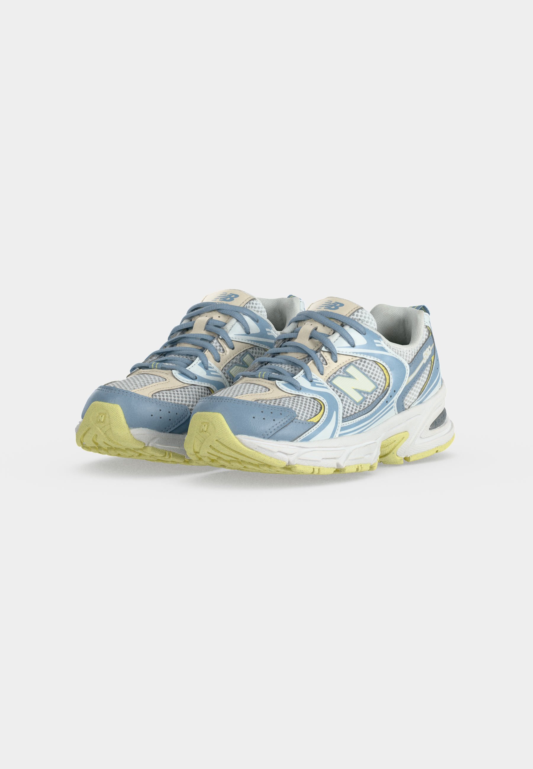 Par de zapatillas para correr azules, beige y amarillas con cordones y tela de malla, colocadas una al lado de la otra sobre un fondo claro y liso.
