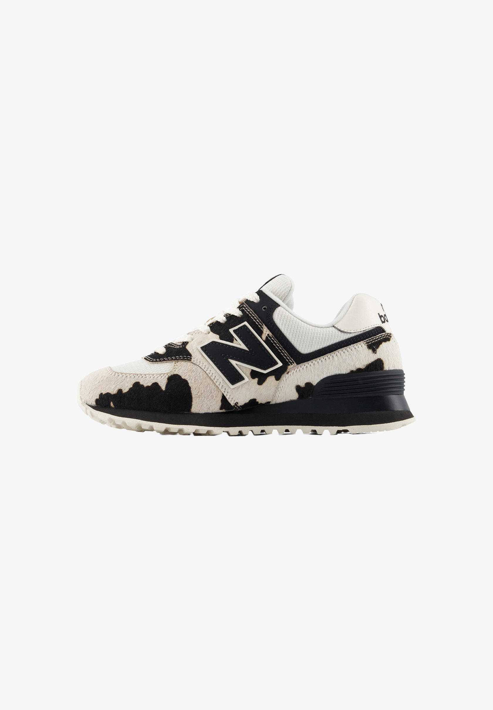Zapatilla New Balance blanca y negra con estampado de vaca, parte superior de malla, suela negra y logo grande "N" en el lateral.