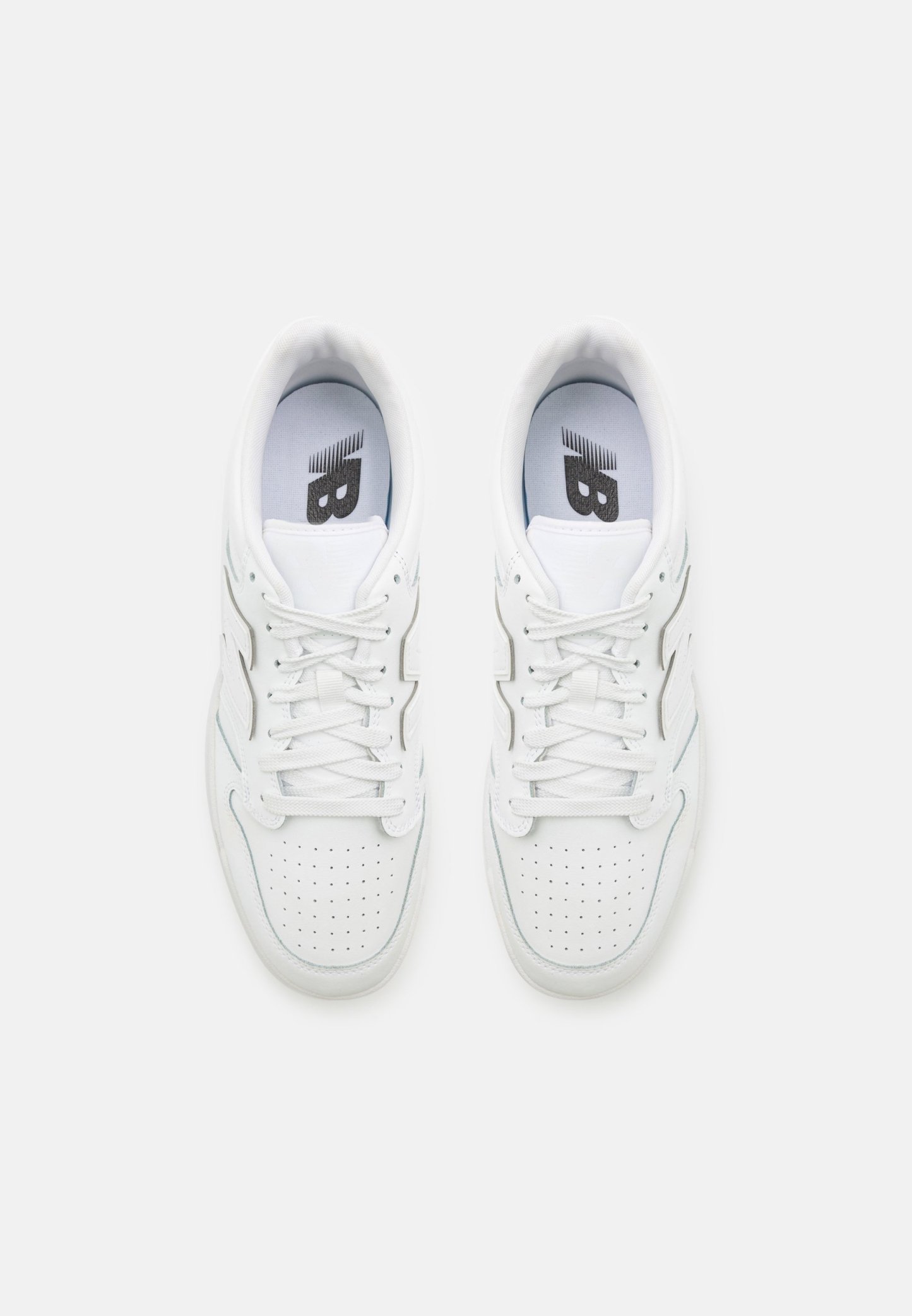 Zapatillas blancas con una parte superior de cuero suave, puntera perforada para transpirabilidad, cordones planos y un logo en la lengüeta. Diseño minimalista.