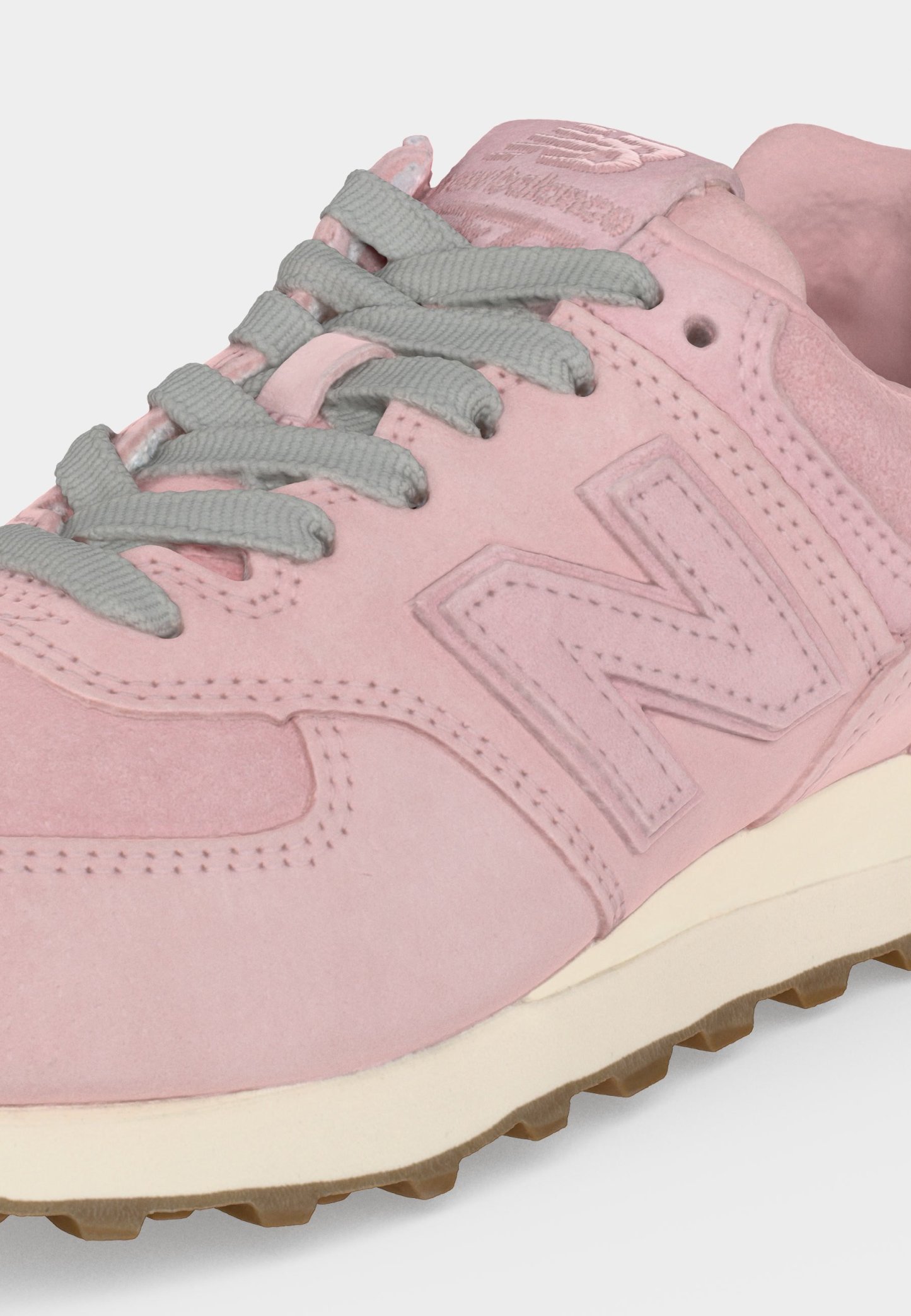 Zapatilla de ante rosa con cordones grises, detalles cosidos y una suela blanca con banda de rodadura de goma marrón, mostrando las partes lateral y superior.