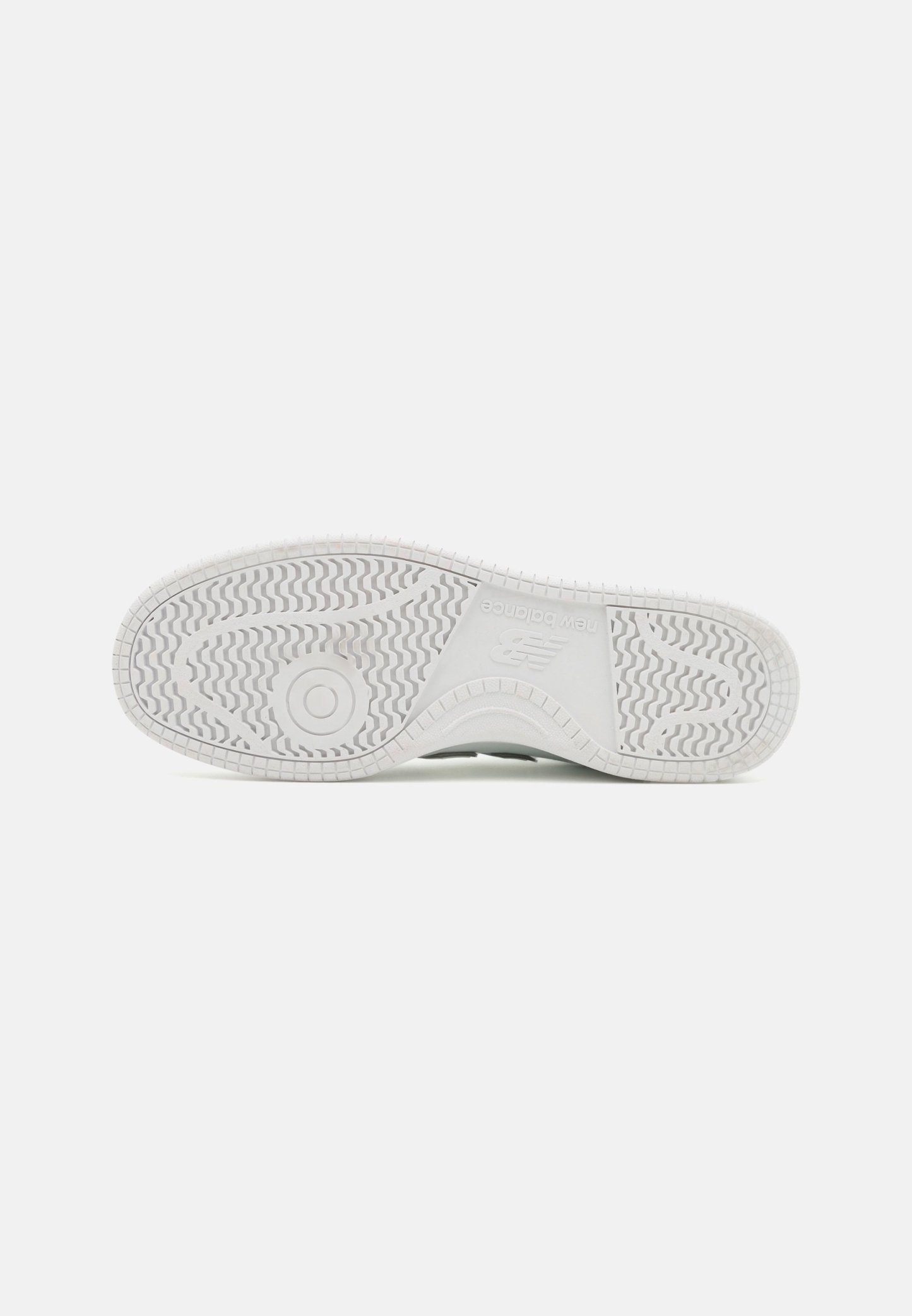 Suela de zapatilla de goma blanca con patrones de textura, que presenta un emblema circular y una sutil marca en la entresuela.