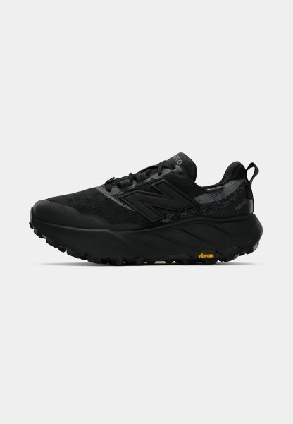 Zapatilla de trail running negra con parte superior de malla transpirable, suela acolchada y suela exterior de goma texturizada. Presenta un logotipo prominente en el costado.