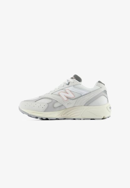 Zapatilla New Balance blanca y gris con superposiciones de malla y ante, suela color crema y logo rosa "N" en el lateral, vista desde el exterior.