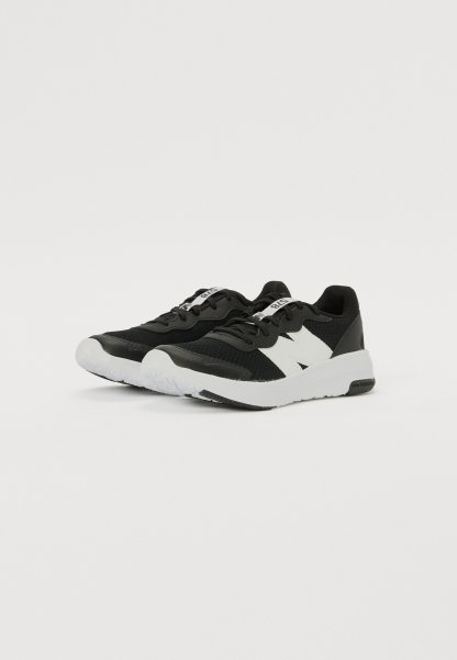 Zapatillas deportivas negras con una parte superior texturizada, acentos blancos y una suela de goma blanca. Incluyen cordones y un logotipo prominente en el lateral.