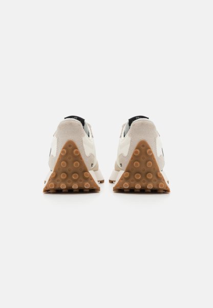 Par de zapatillas beige claras vistas desde atrás, con suelas de tacón triangulares marrones texturizadas con agarres circulares sobre un fondo blanco.