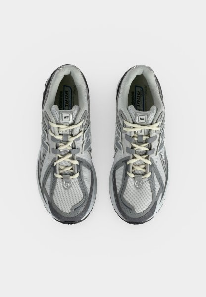 Par de zapatillas de correr grises y negras vistas desde atrás sobre un fondo blanco, con suelas acolchadas y logo de la marca en el talón.