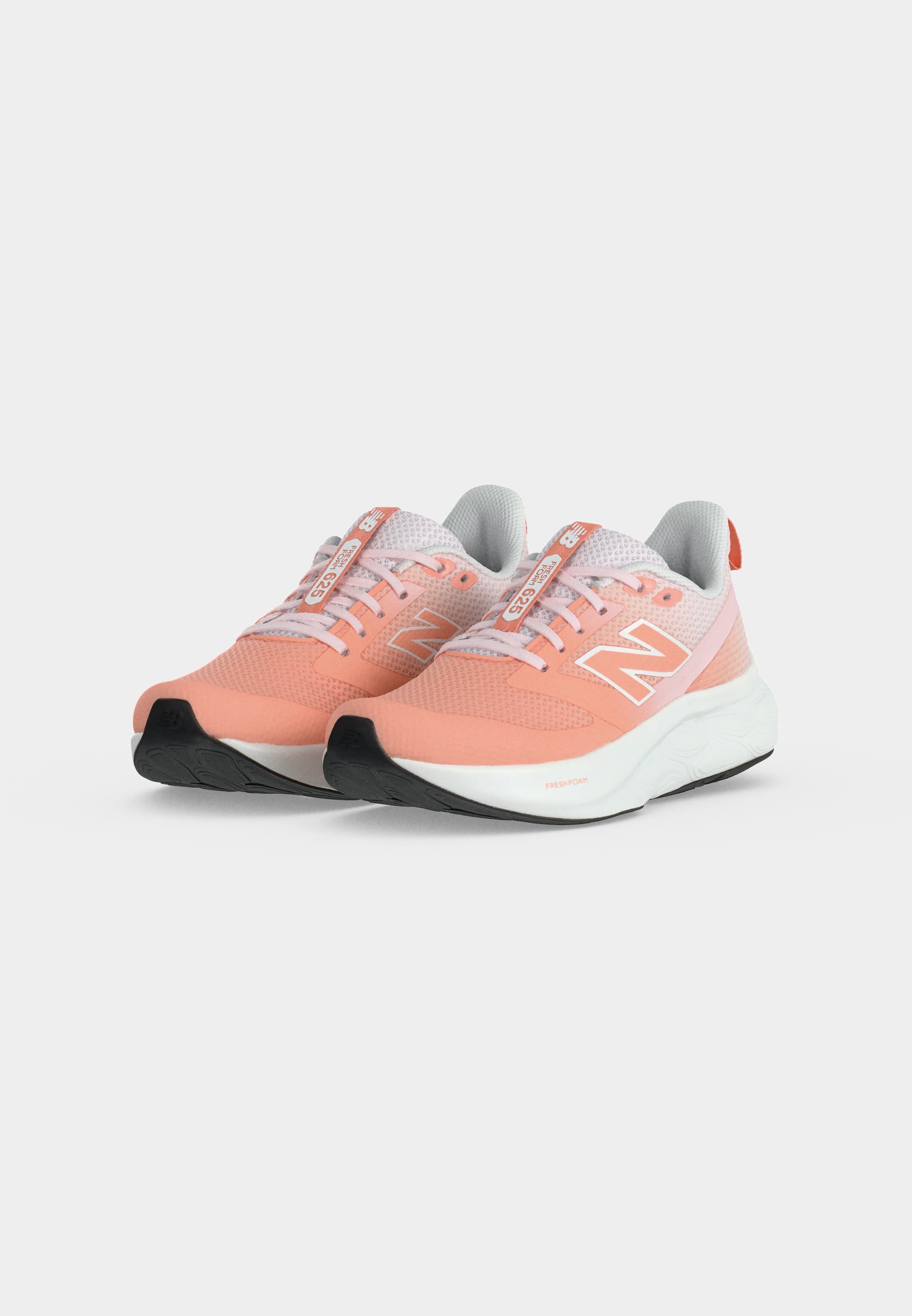 Par de zapatillas de correr New Balance coral rosa y blancas con parte superior de malla y suelas de caucho negro sobre fondo blanco.