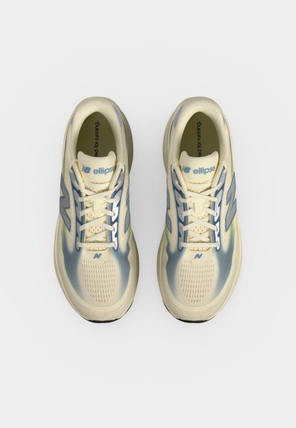 Par de zapatillas de correr New Balance en crema y azul vistas desde arriba con los cordones atados y el nombre de la marca visible en las lengüetas.