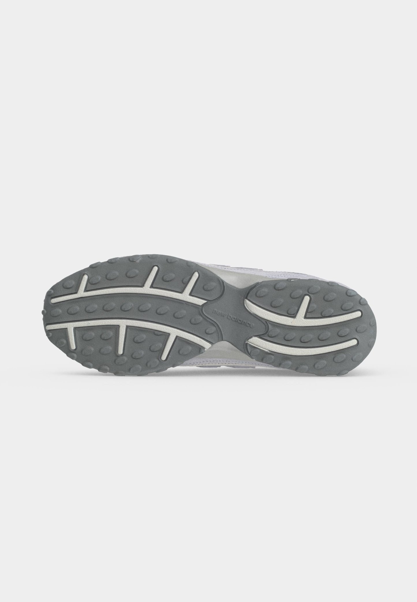 Suela de zapatilla gris y blanca con banda de rodadura de goma texturizada y logo de "New Balance" en el centro sobre un fondo claro y liso.