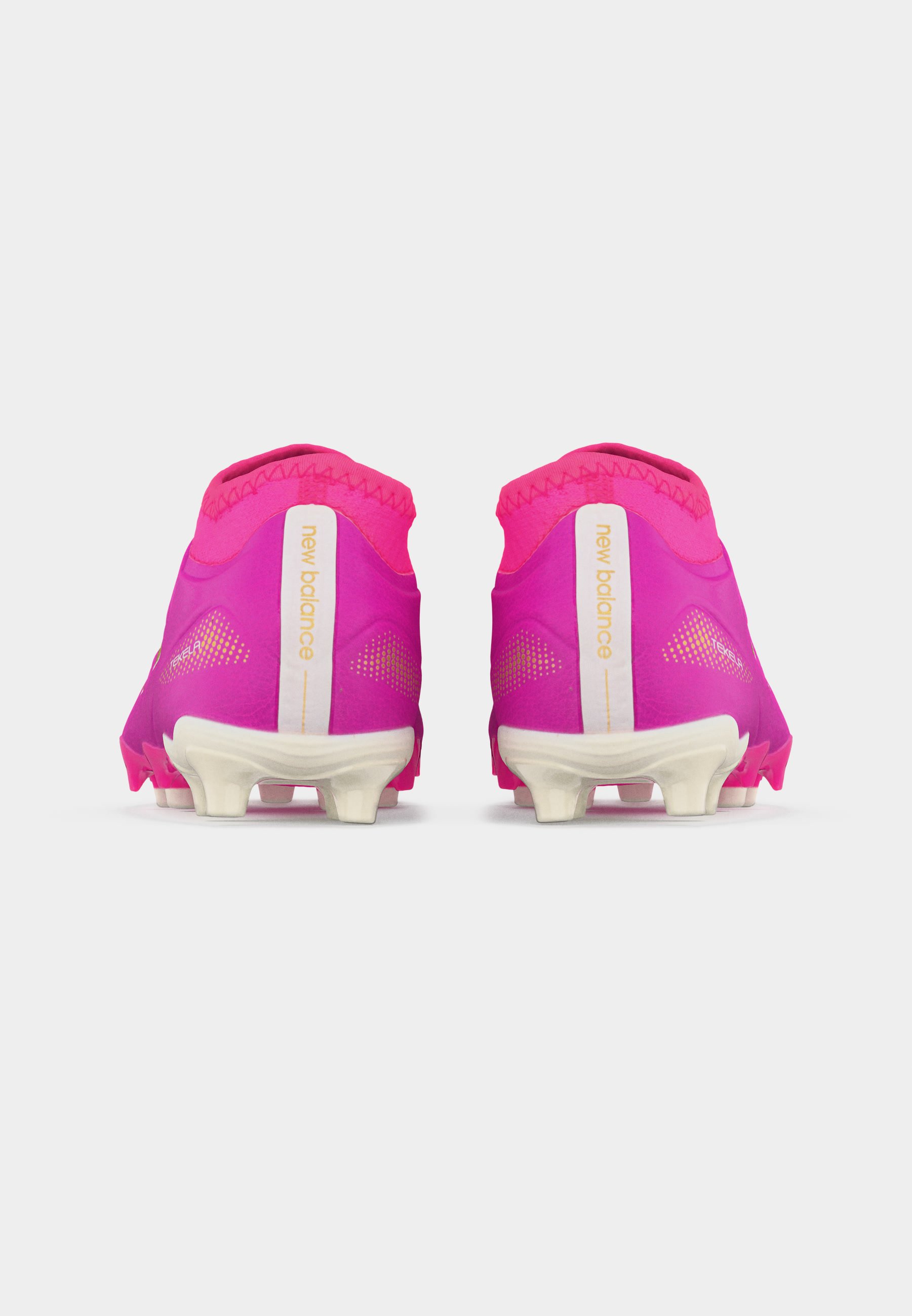 Par de botas de fútbol rosas de New Balance mostradas desde atrás con suelas blancas con tacos y el logotipo de la marca en las lengüetas del talón.