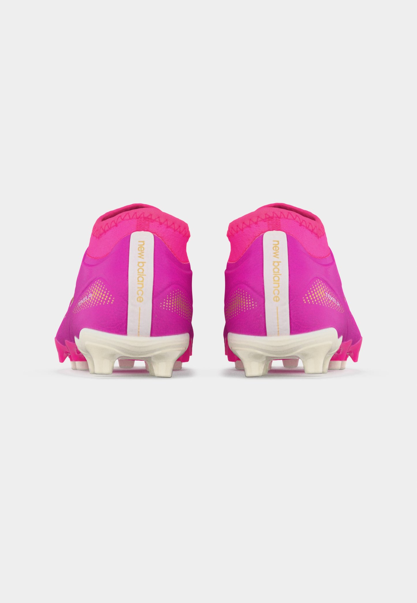 Par de botas de fútbol rosas de New Balance mostradas desde atrás con suelas blancas con tacos y el logotipo de la marca en las lengüetas del talón.