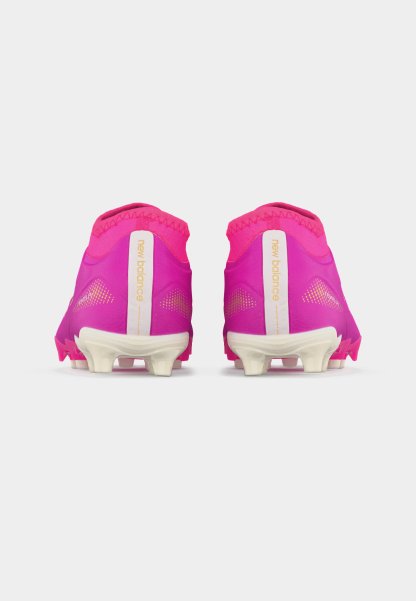 Par de botas de fútbol rosas de New Balance mostradas desde atrás con suelas blancas con tacos y el logotipo de la marca en las lengüetas del talón.
