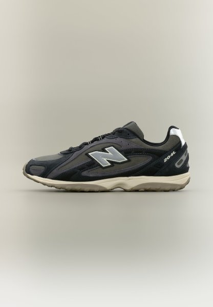 Zapatilla New Balance 204L en negro y gris con logo blanco y suela beige, vista de perfil sobre un fondo liso.