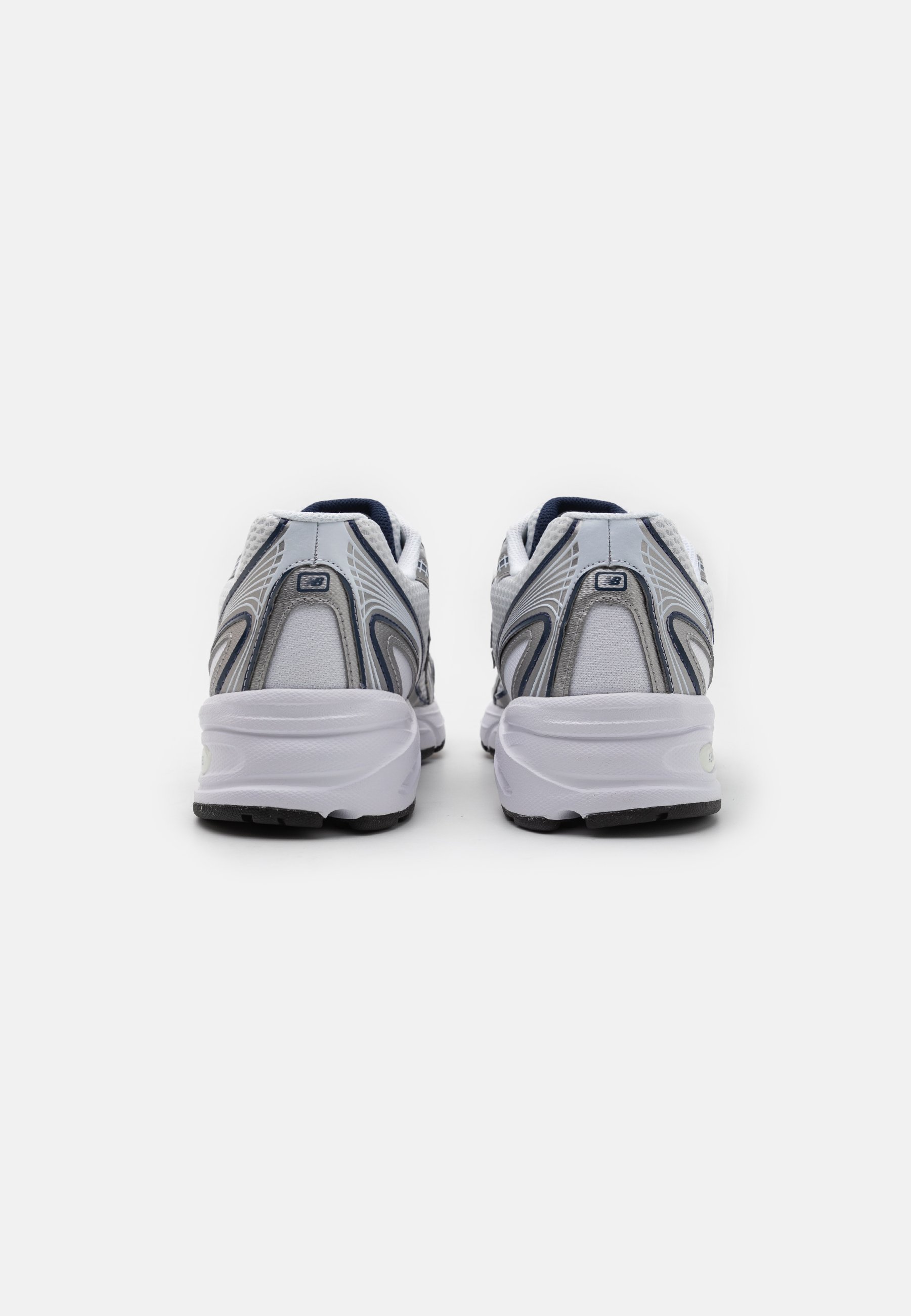 Zapatillas deportivas blancas y grises con parte superior de malla, diseño curvado y suela texturizada. Presenta un pequeño logo en la parte trasera y un talón contorneado.