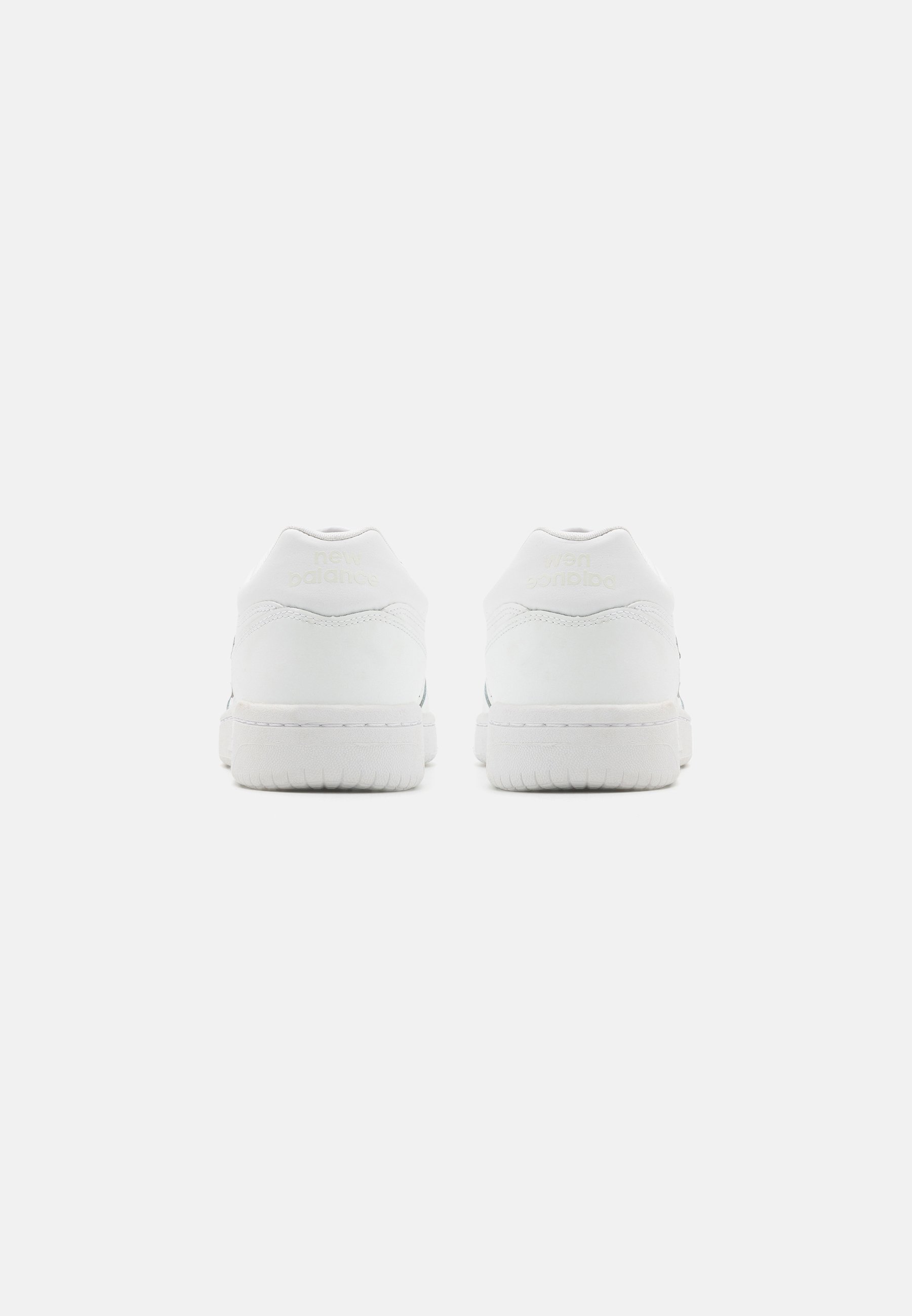 Zapatillas blancas con parte superior de cuero suave, talón acolchado y suela de goma texturizada. Presenta un logotipo sutil en el talón. Diseño minimalista.