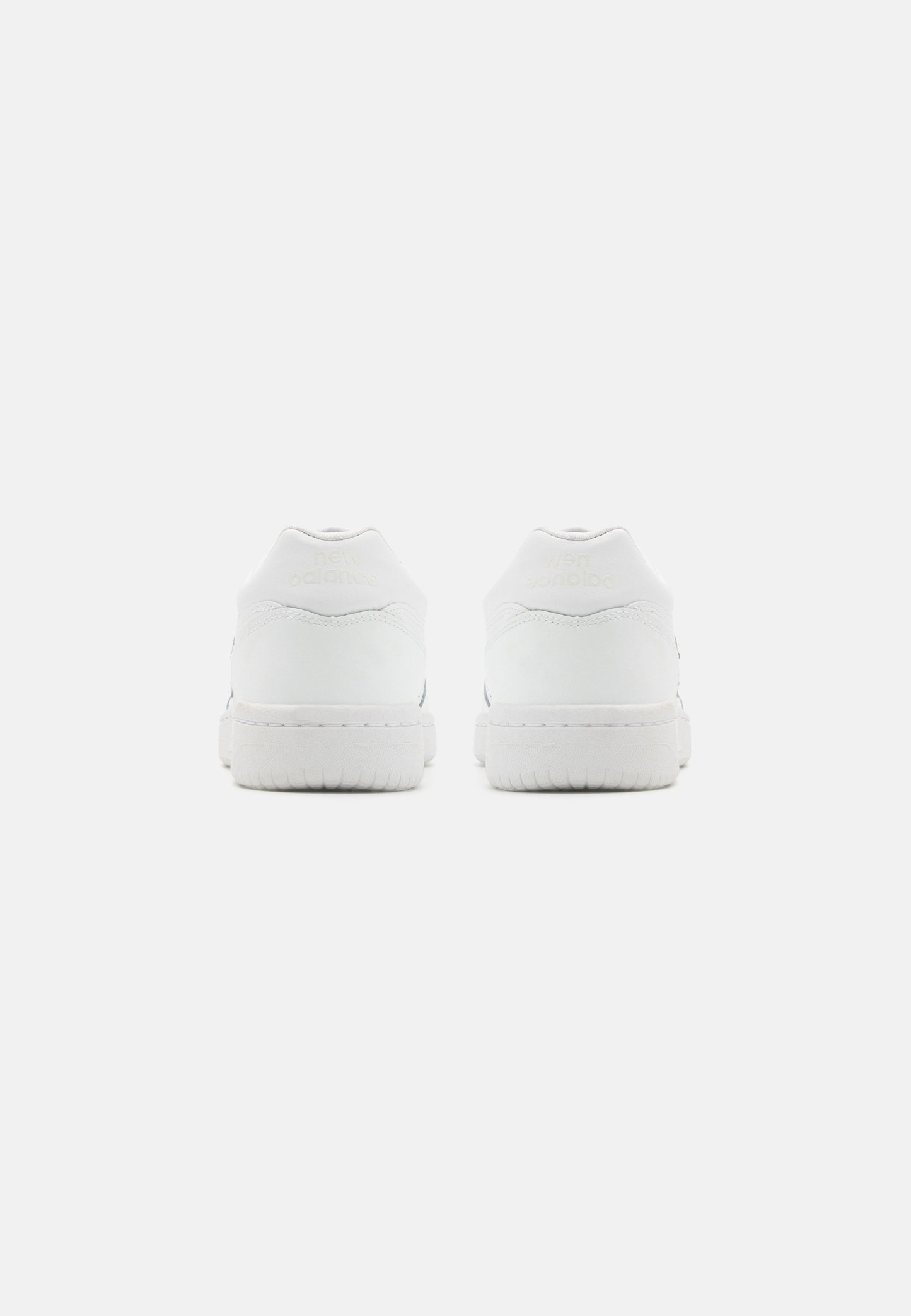 Zapatillas blancas con parte superior de cuero suave, talón acolchado y suela de goma texturizada. Presenta un logotipo sutil en el talón. Diseño minimalista.