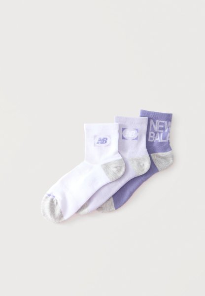 Tres pares de calcetines tobilleros en blanco y tonos de morado, cada uno con punteras y tacones grises y logos de New Balance en los puños.