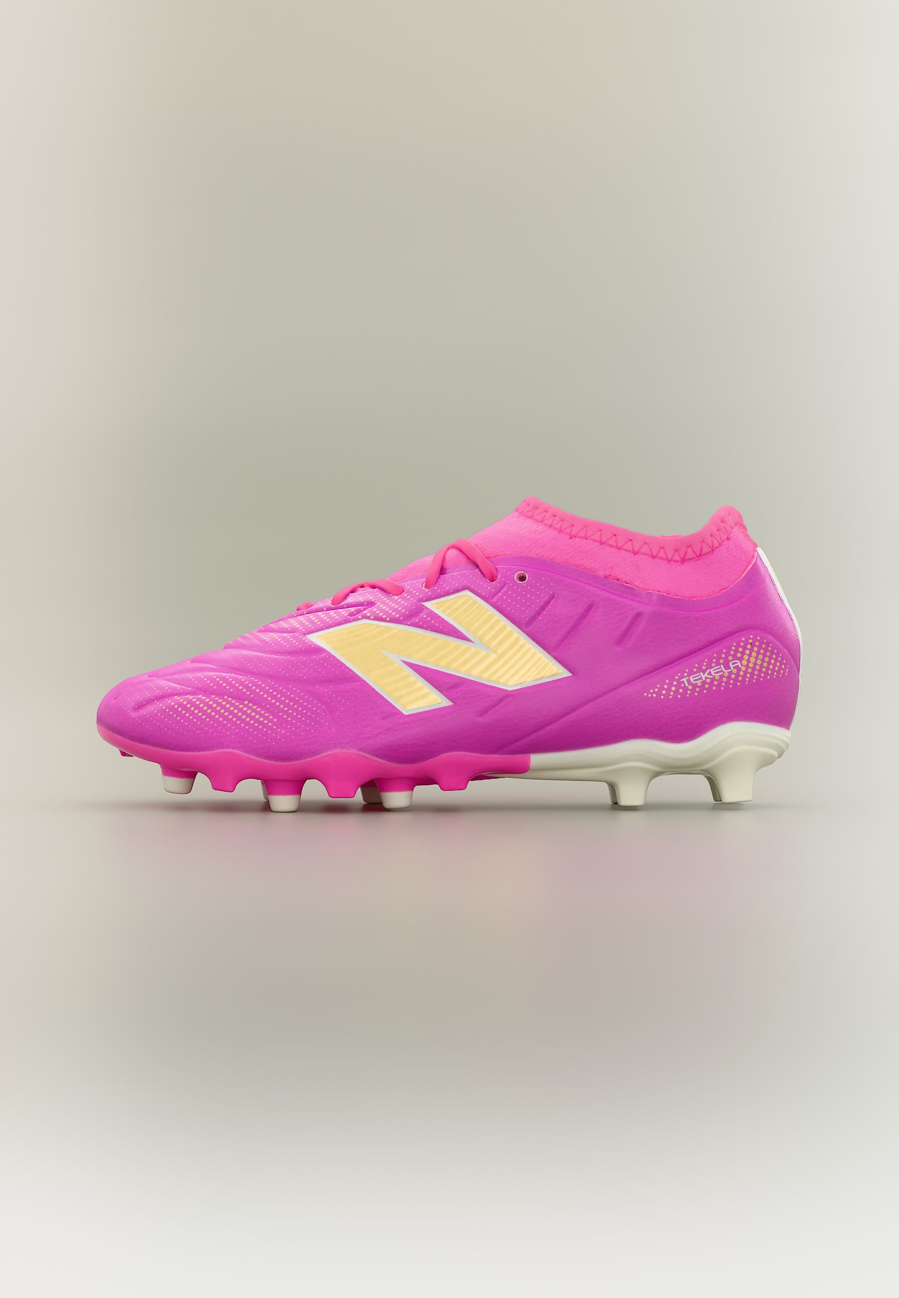 Taco de fútbol de color rosa brillante con logo "N" amarillo, cordones rosas y tacos blancos, diseñado para jugar en terreno firme.