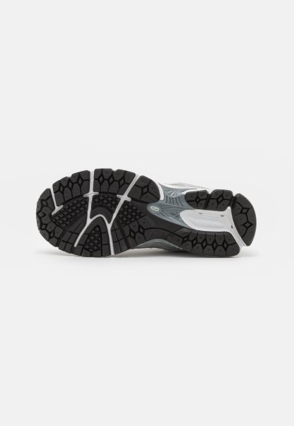 Suela de zapatilla deportiva con un diseño de goma negra, patrones hexagonales texturizados, acentos en blanco y una forma curva y ergonómica.