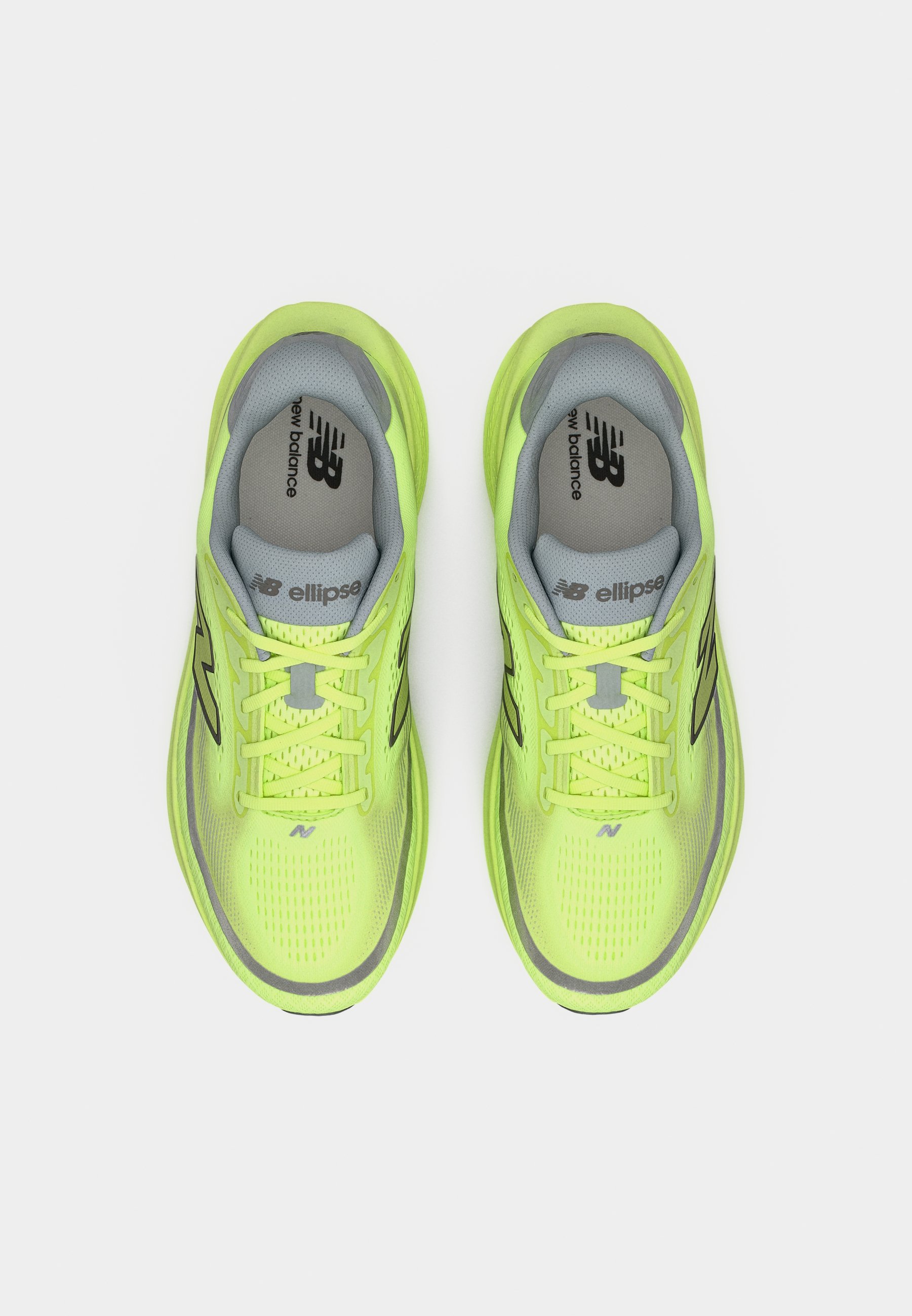 Par de zapatillas de correr New Balance en un brillante color verde amarillo, con plantillas y cordones grises, vistas desde arriba sobre un fondo blanco.