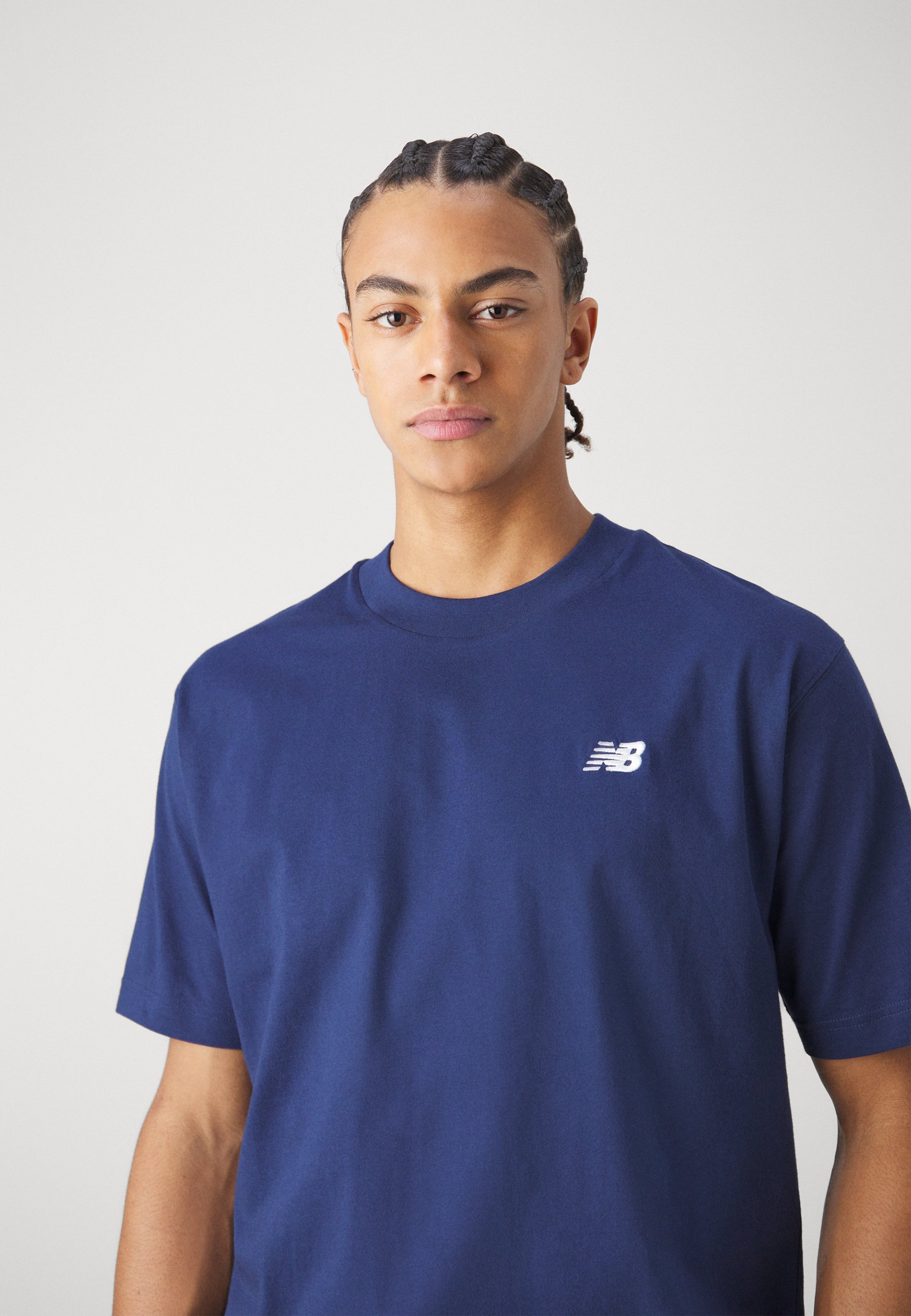Camiseta de algodón azul marino con cuello redondo y mangas cortas, que presenta un pequeño logo blanco "NB" en la zona del pecho izquierdo.