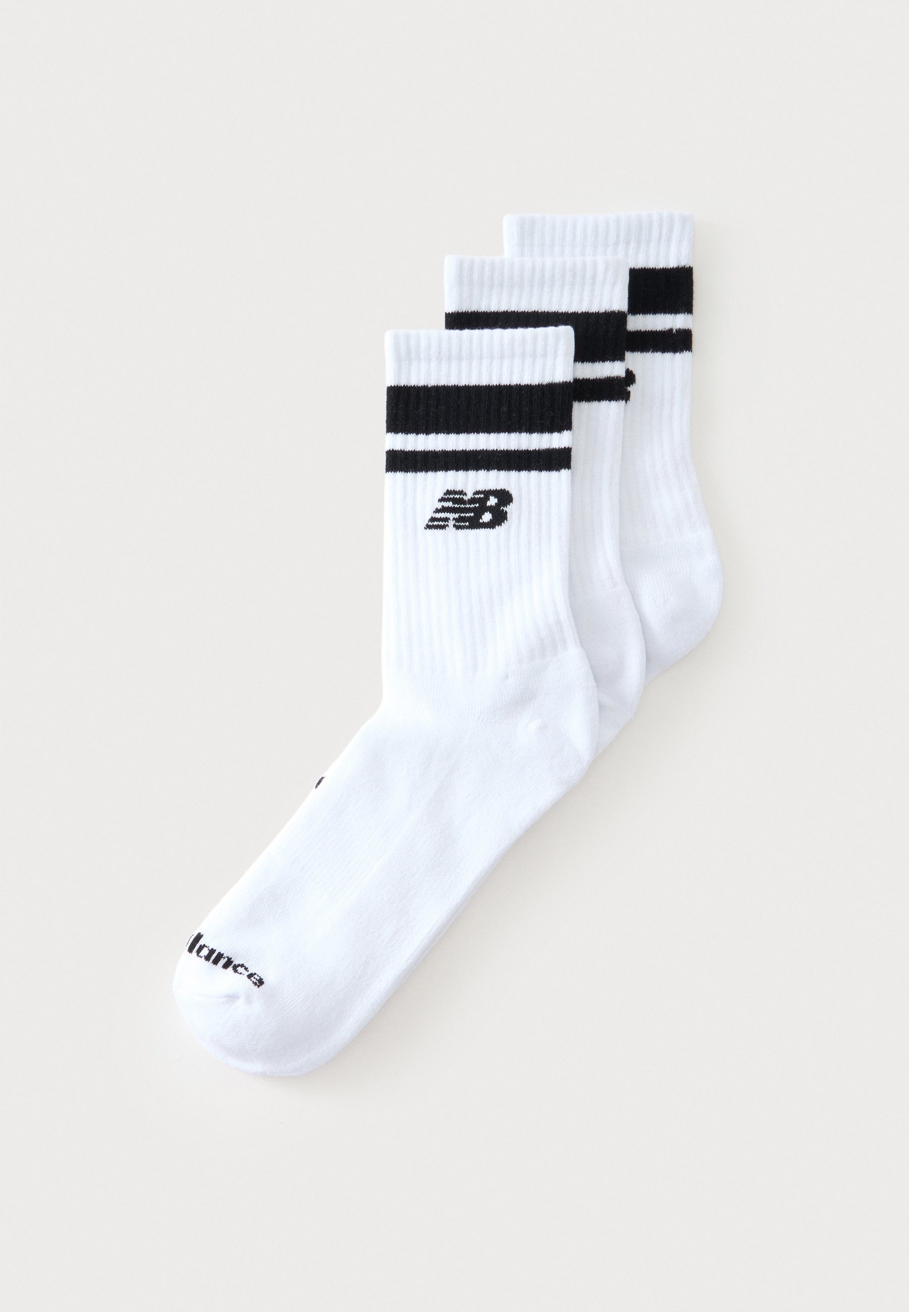 Tres calcetines blancos de tripulación con rayas negras en la parte superior y el logotipo de New Balance en los laterales, dispuestos superpuestos sobre un fondo blanco.