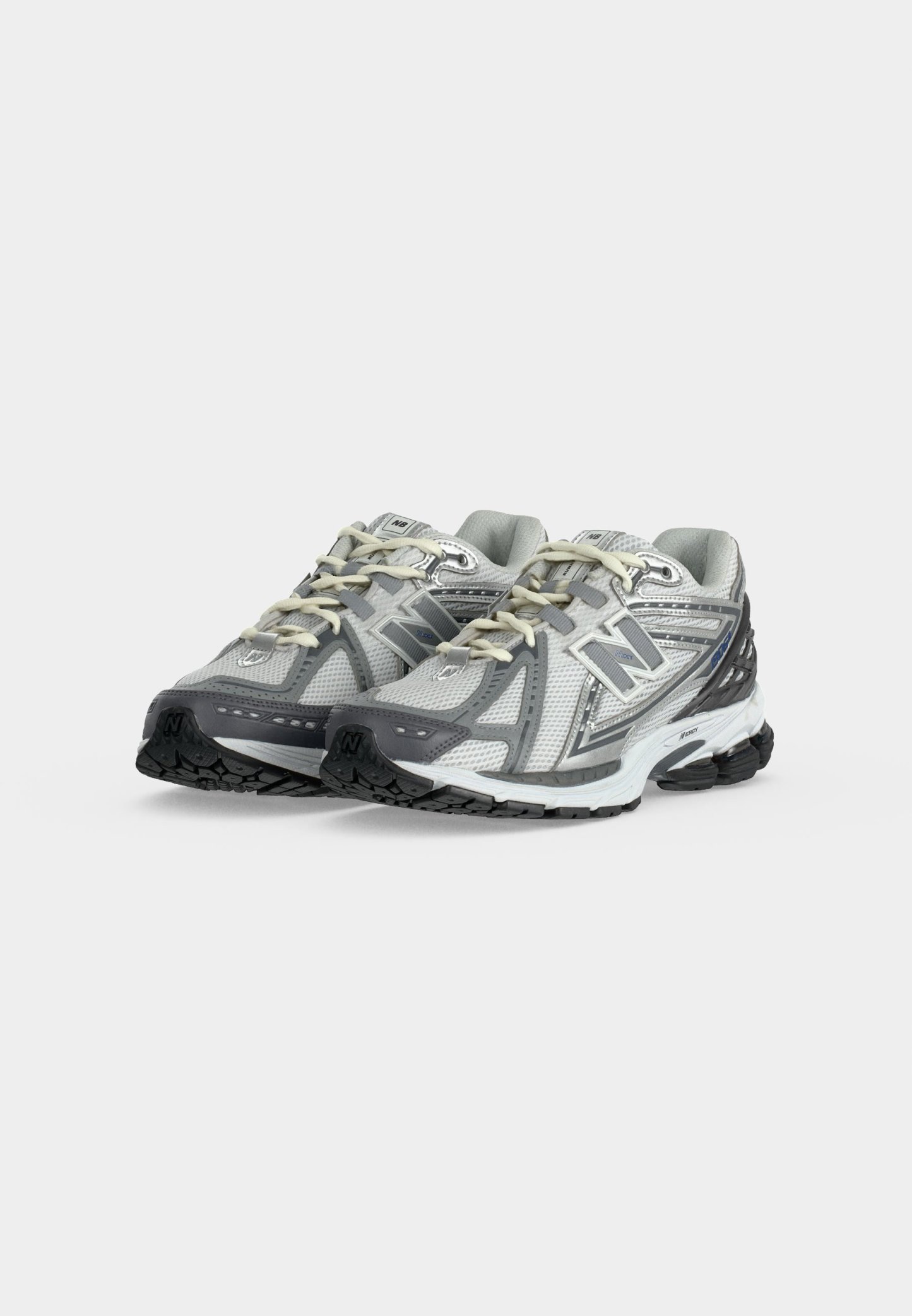 Zapatilla de running New Balance en plata y gris con parte superior de malla, diseño con cordones y suela acolchada con detalles en negro.