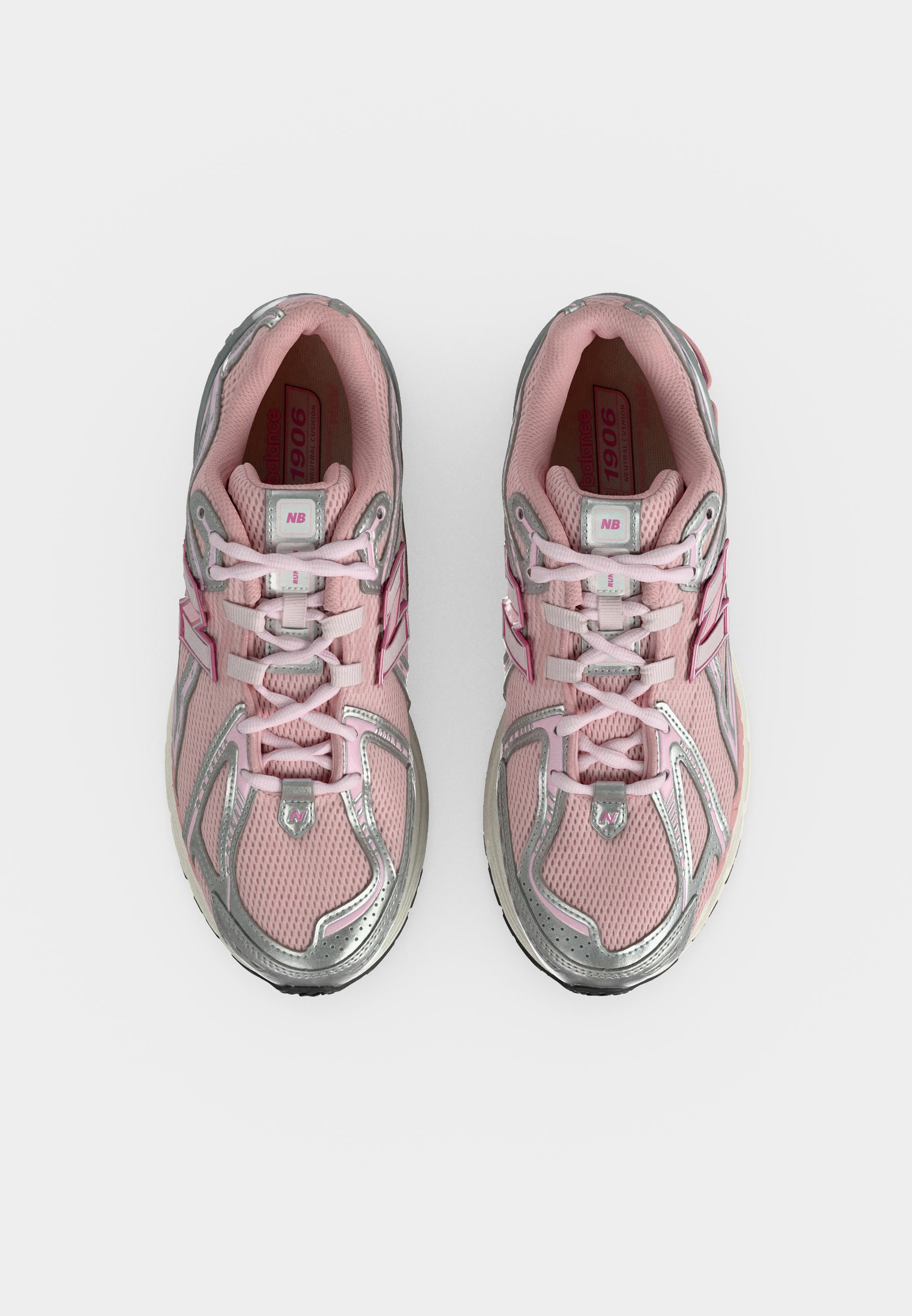 Par de zapatillas para correr New Balance rosas y plateadas con cordones, vista desde arriba sobre un fondo blanco.