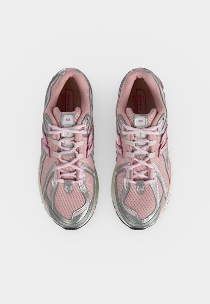 Par de zapatillas para correr New Balance rosas y plateadas con cordones, vista desde arriba sobre un fondo blanco.
